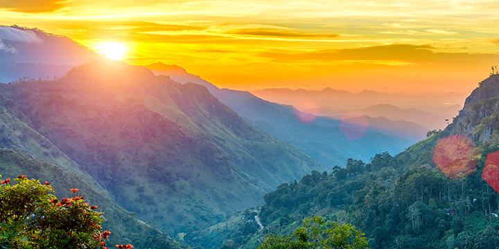 Golden sunrise illuminating the mountain ridges and cloud-filled valley of Ella